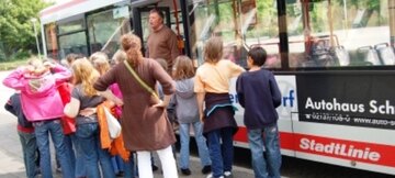 Eine Schulklasse steht vor einem Bus