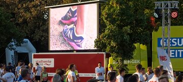 Eine große aufgebaute LED-Wand. Davor sind mehrere Menschen zu sehen.